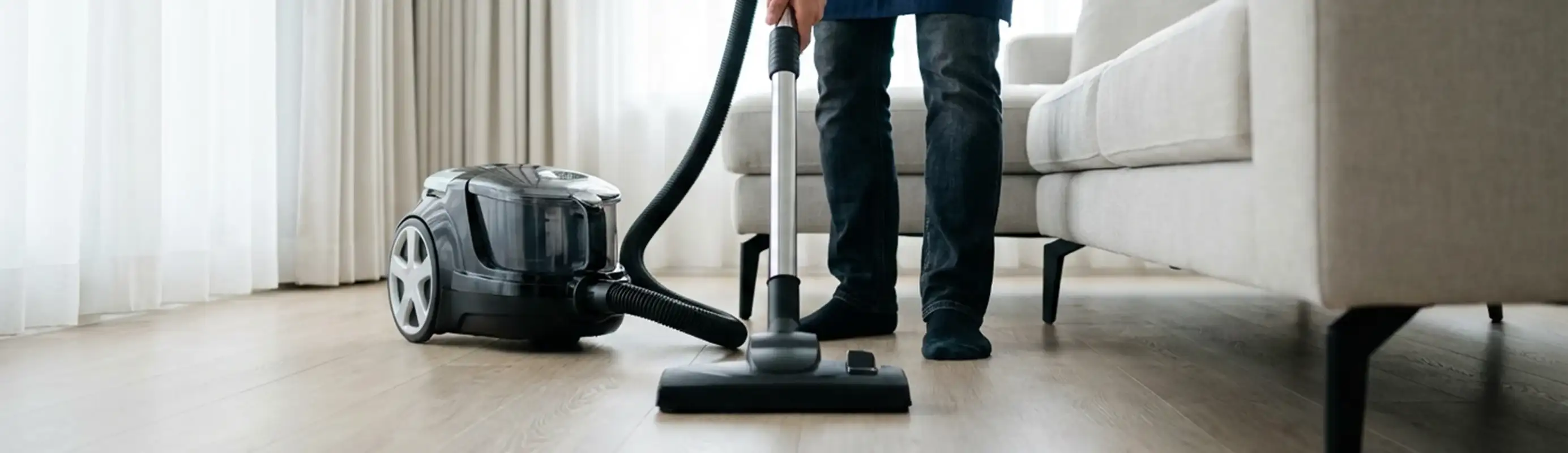 Professional house cleaner vacuuming a living room floor with a canister vacuum cleaner, Philadelphia, PA.