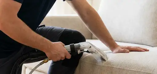 Professional upholstery cleaner deep-cleaning a fabric sofa with a handheld extraction tool, Philadelphia, PA.